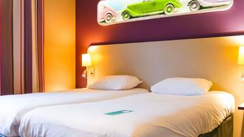 A hotel room with a bed, two bedside lamps, and a wall-mounted picture of vintage cars.