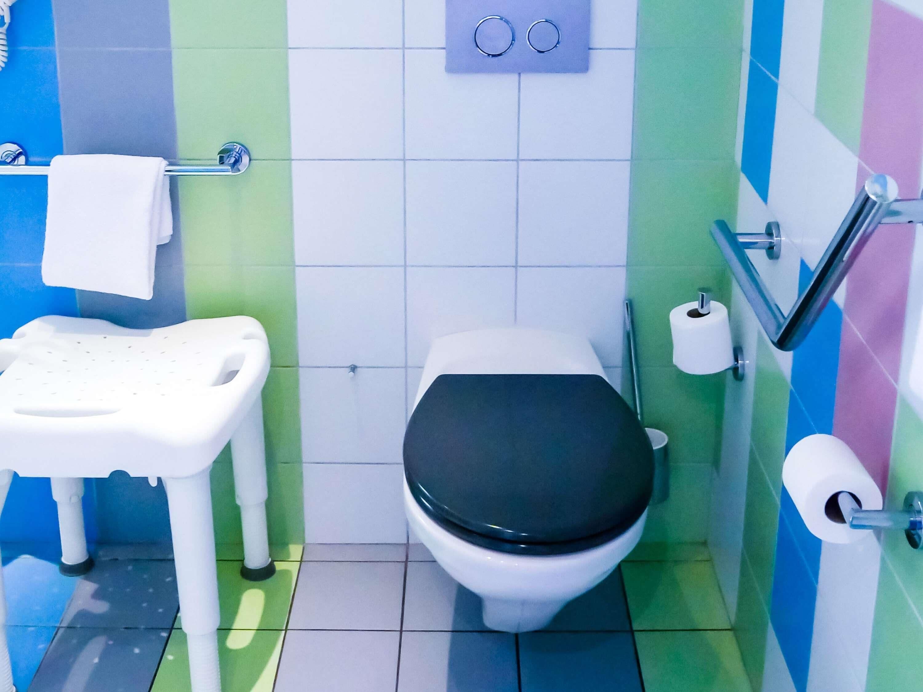 A small bathroom with a toilet, a child potty, and a hand sanitizer dispenser.