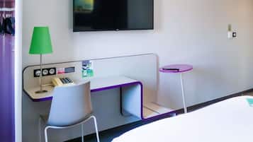 Una habitación de hotel con escritorio, silla, televisor y una mesita.