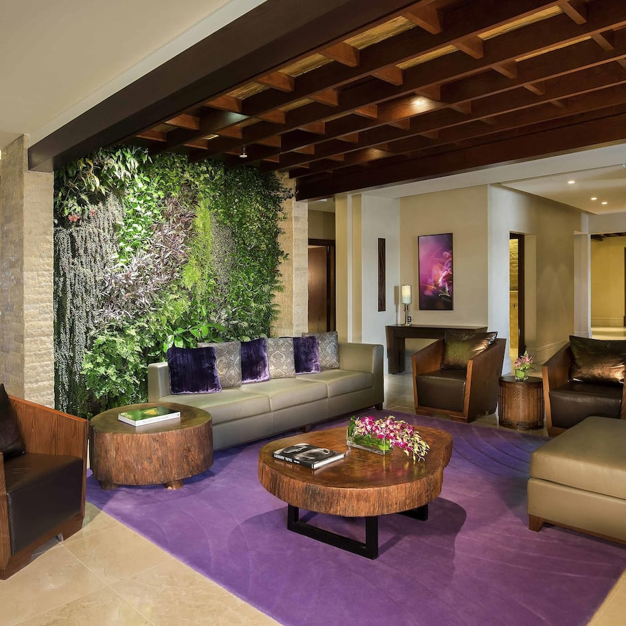 A modern living room with a green wall, a sofa, a coffee table, and a fireplace.