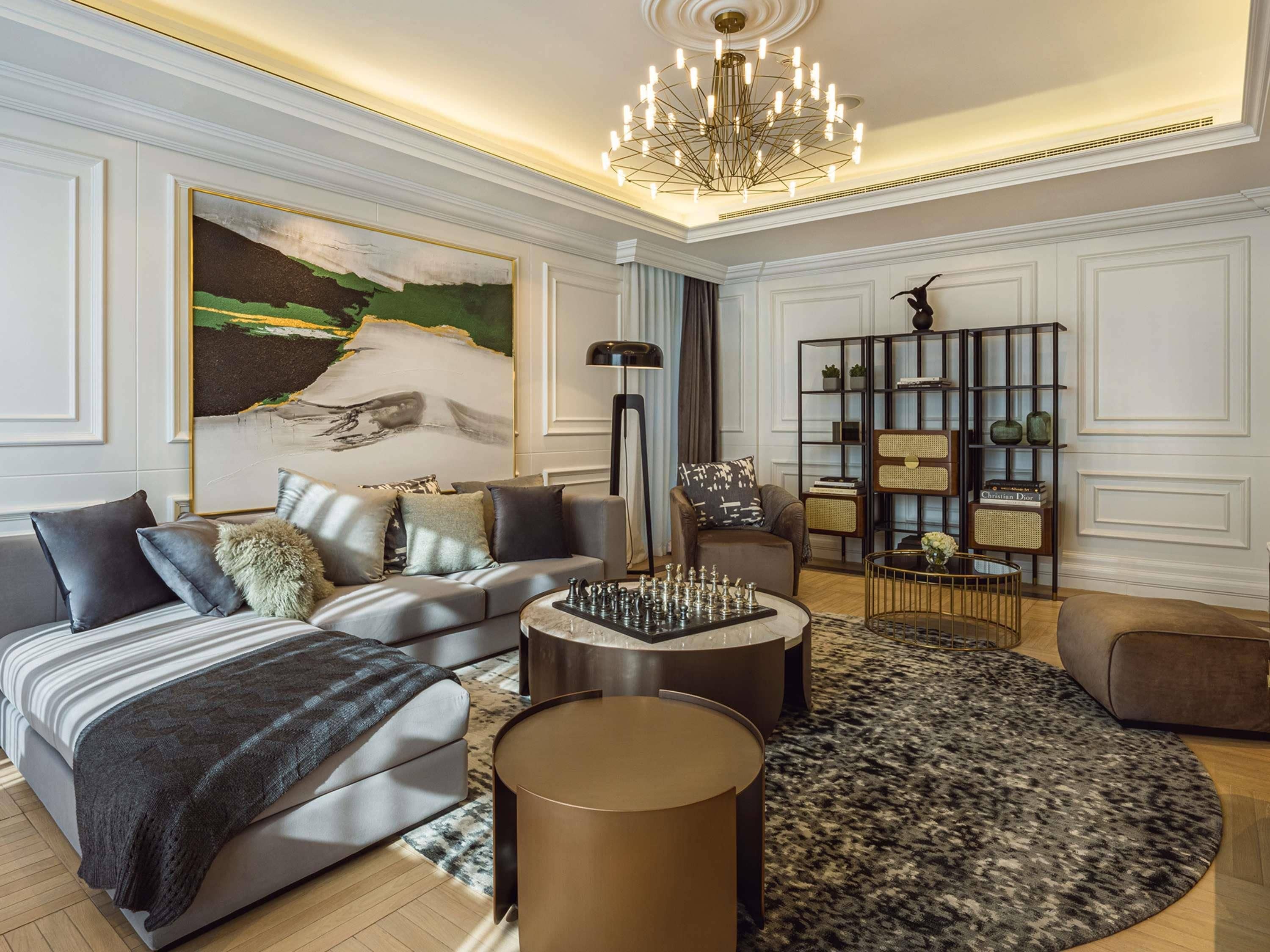 Una sala de estar moderna con un sofá modular, una mesa de centro redonda, una estantería y un candelabro.