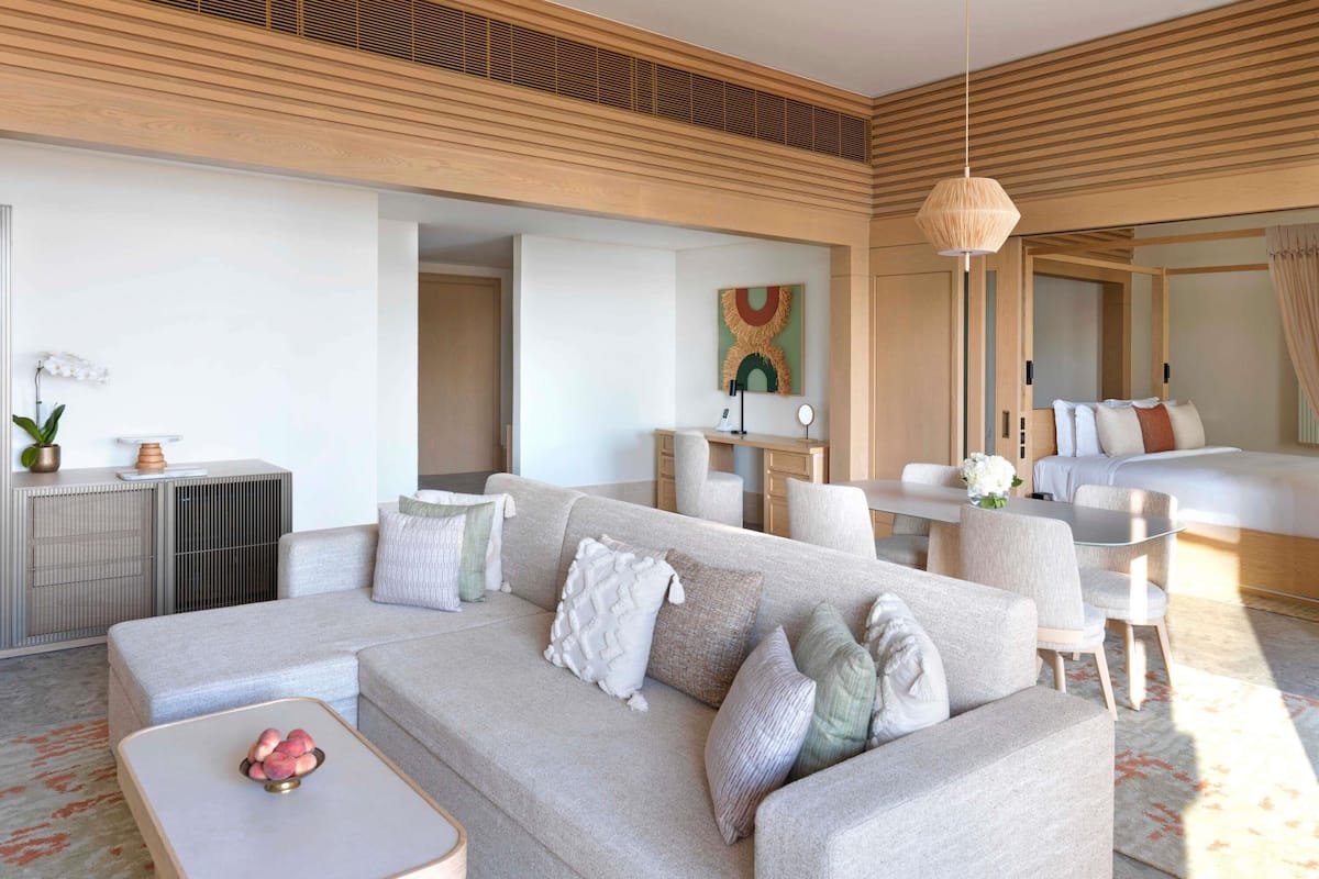 Een moderne woonkamer met een bank, salontafel en een eethoek met stoelen.