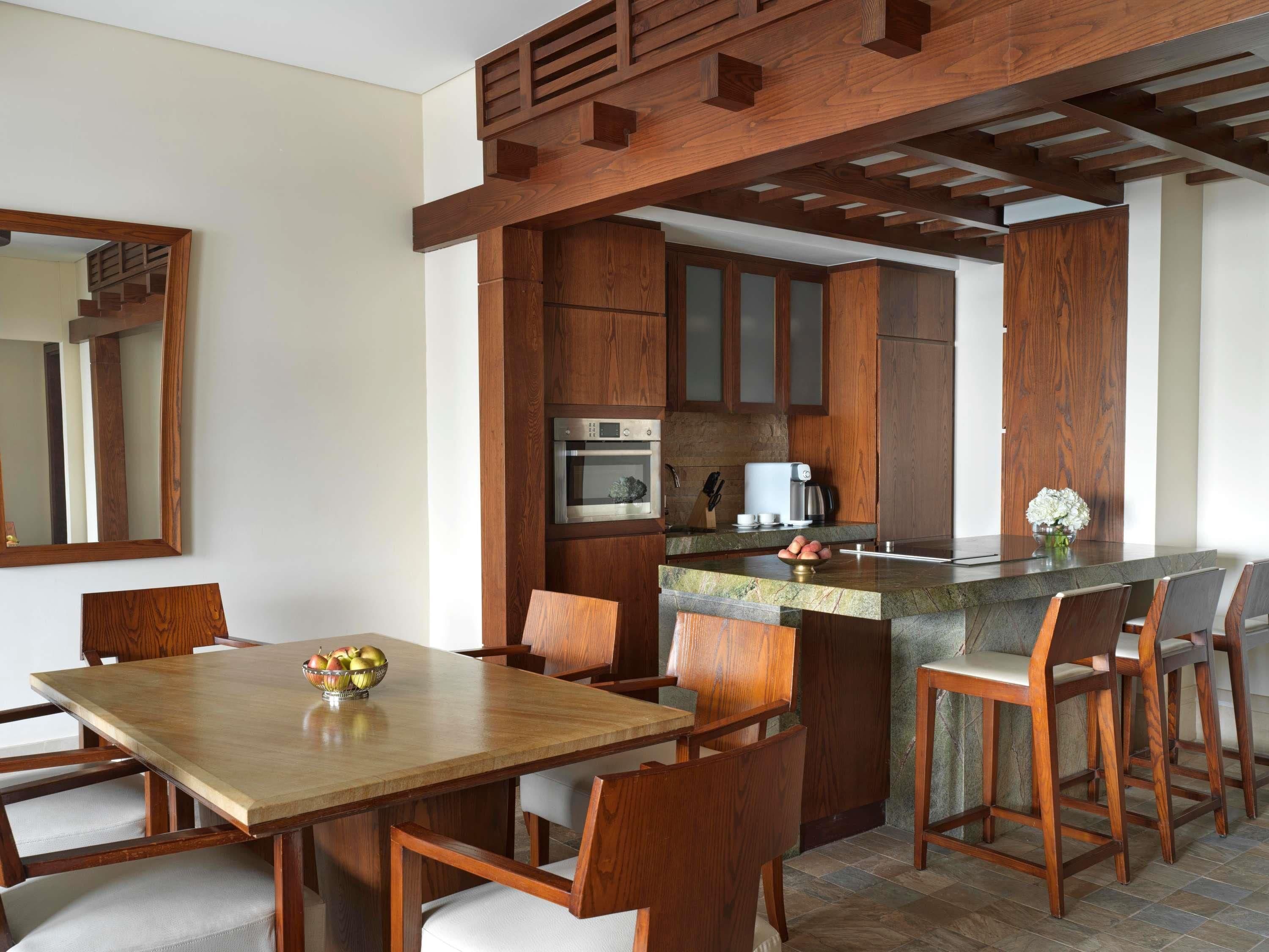 A modern kitchen with wooden cabinetry, a central island, and a dining area with a wooden table and chairs.