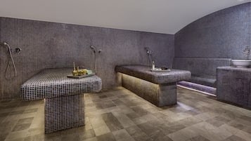 A modern bathroom with a tiled floor, a bench, a sink, and a shower area.