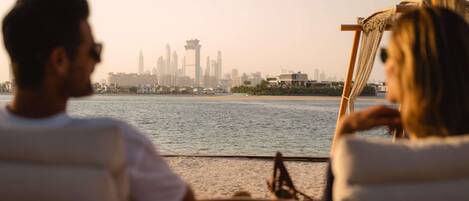 A couple seated at a table by a window overlooking a city skyline and water.