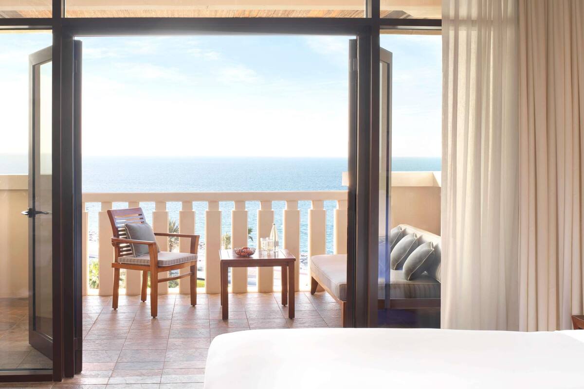 Een hotelkamer met balkon, een bed, een stoel, een tafel en een bank.
