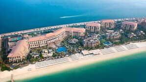 Vista aérea de un complejo turístico con varias construcciones, una playa y un muelle.