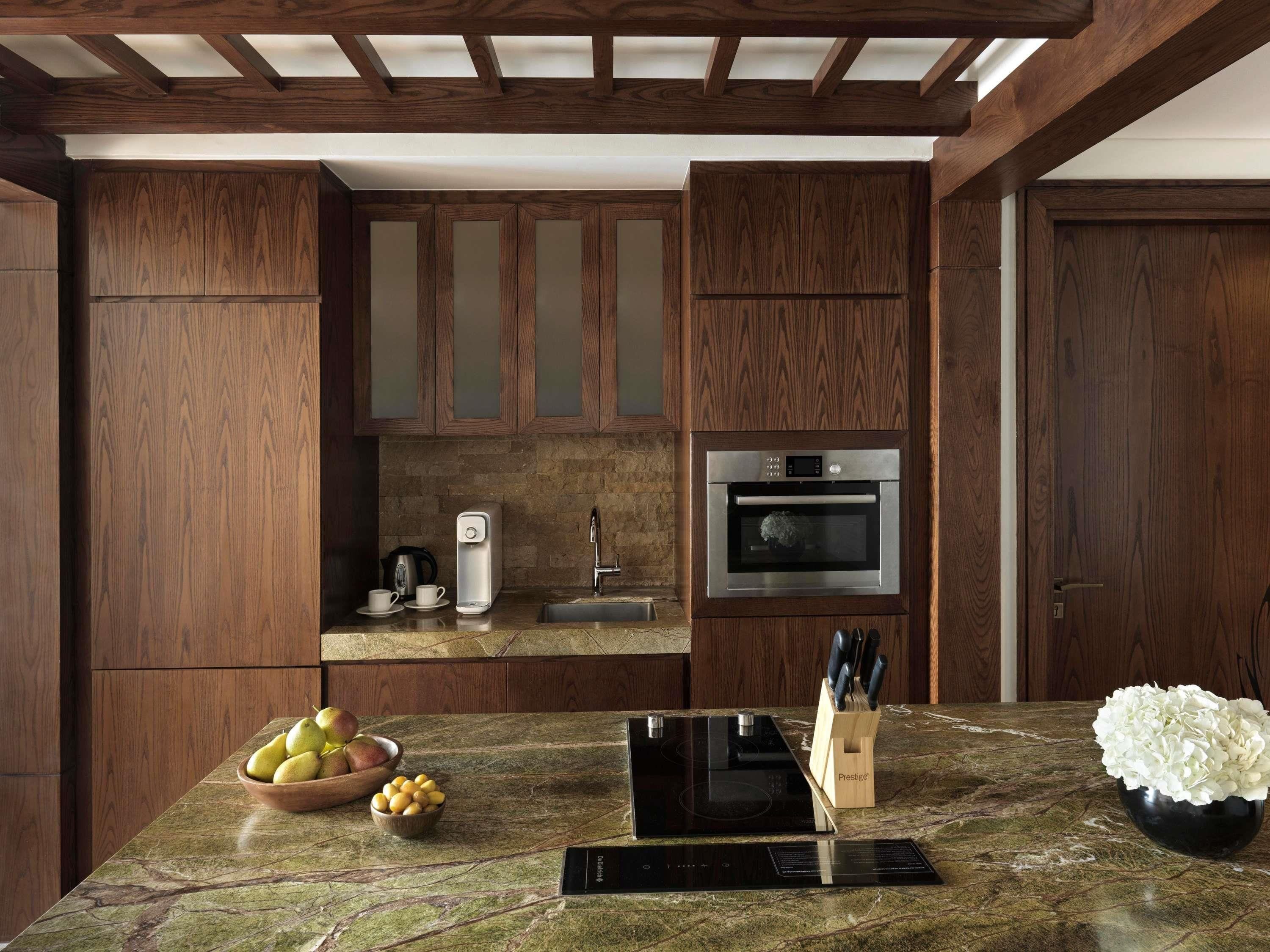 A kitchen with wooden cabinets, a built-in oven, a coffee maker, and a fruit bowl on the counter.