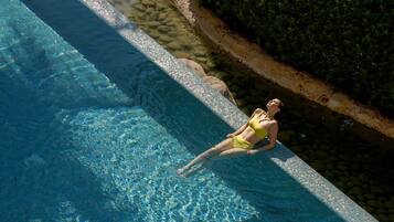 Guests can enjoy a refreshing swim in the pool surrounded by a sandy area and a neatly trimmed hedge.