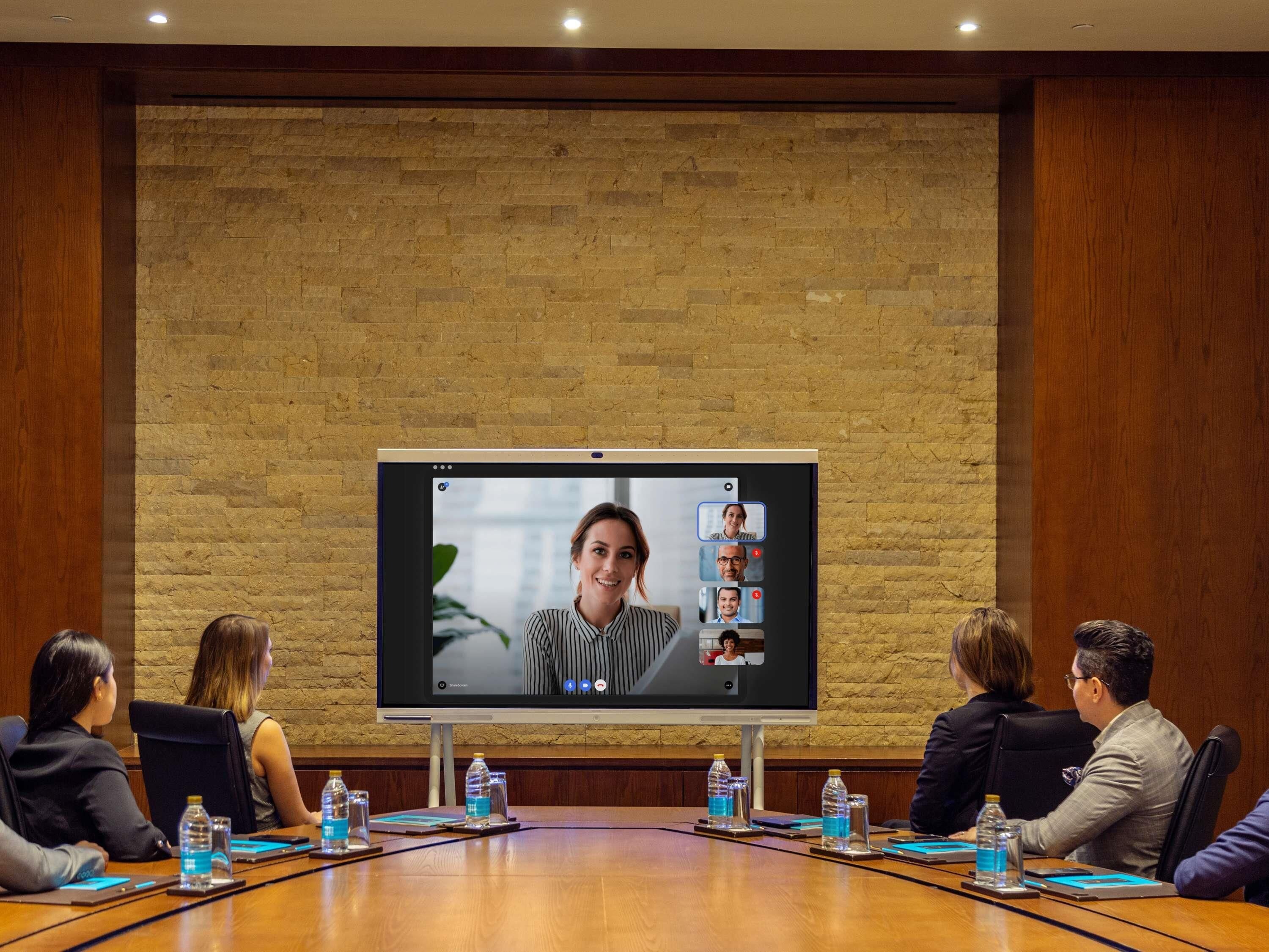 Une salle de conférence équipée d’un grand écran diffusant une vidéoconférence.