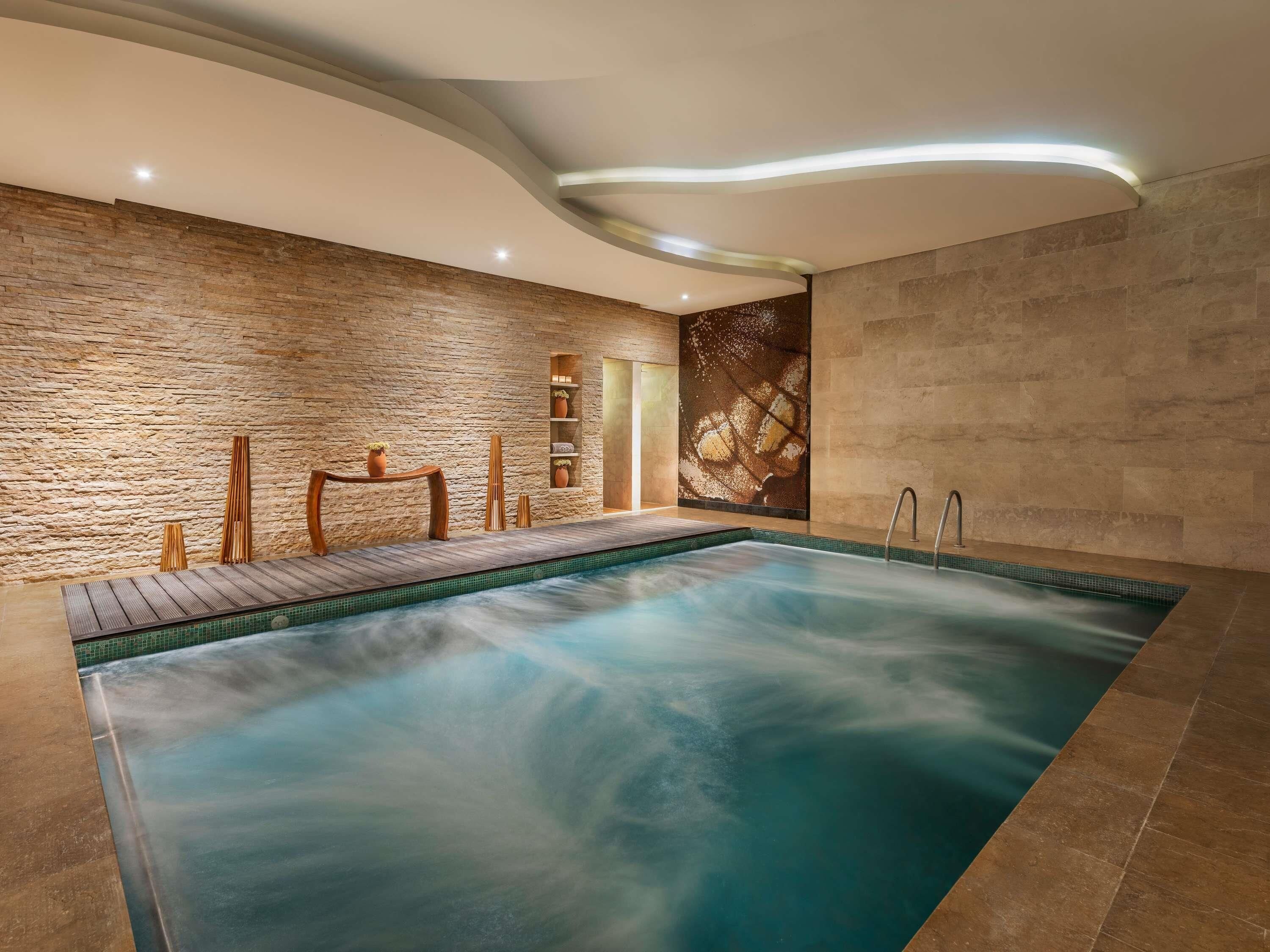 Un área de spa con jacuzzi, muebles de madera y una pared de piedra.