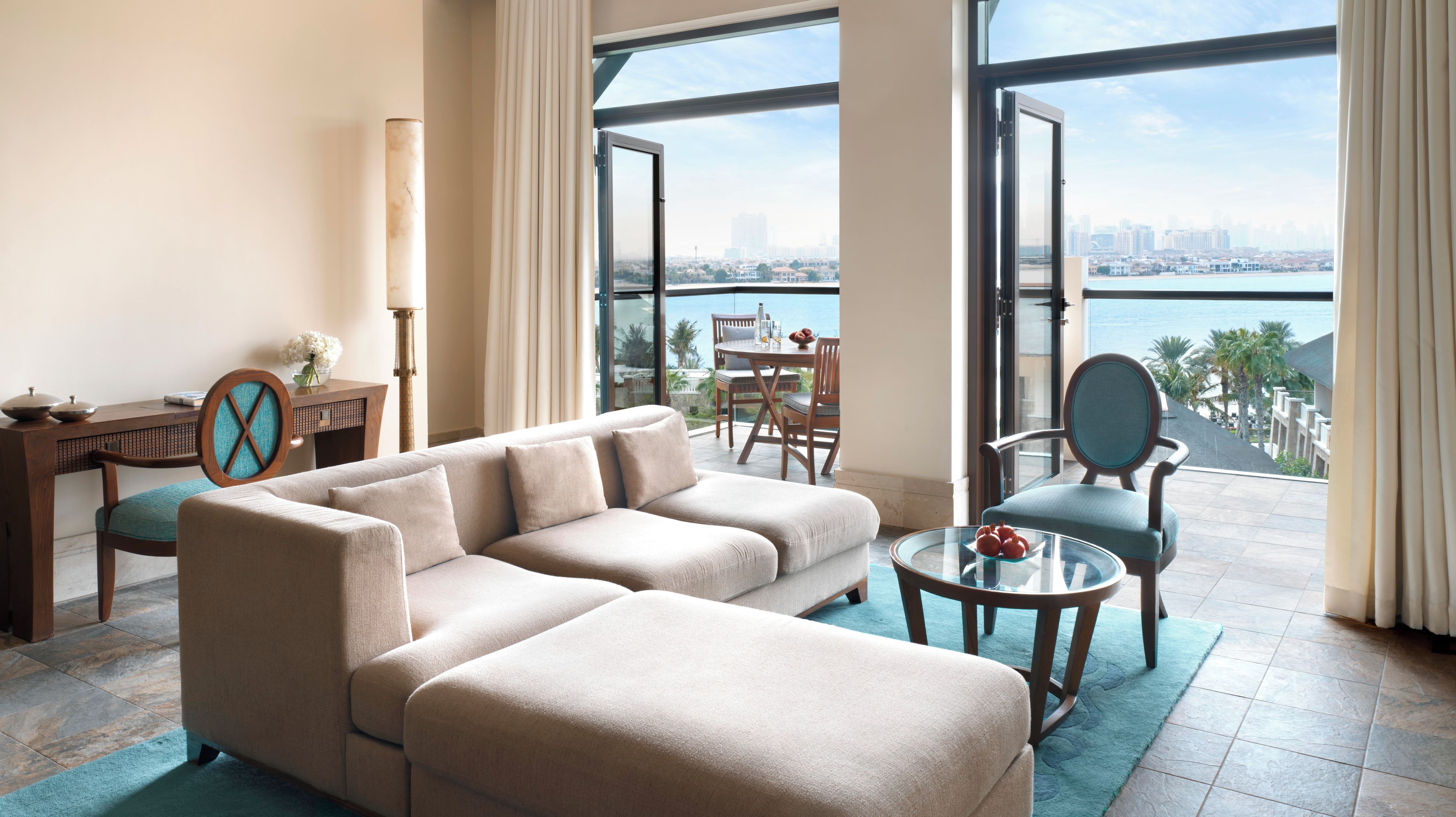 Ein modernes Wohnzimmer mit einer Couch, einem Esstisch und Stühlen, mit Blick auf ein Gewässer und die Stadtlandschaft.