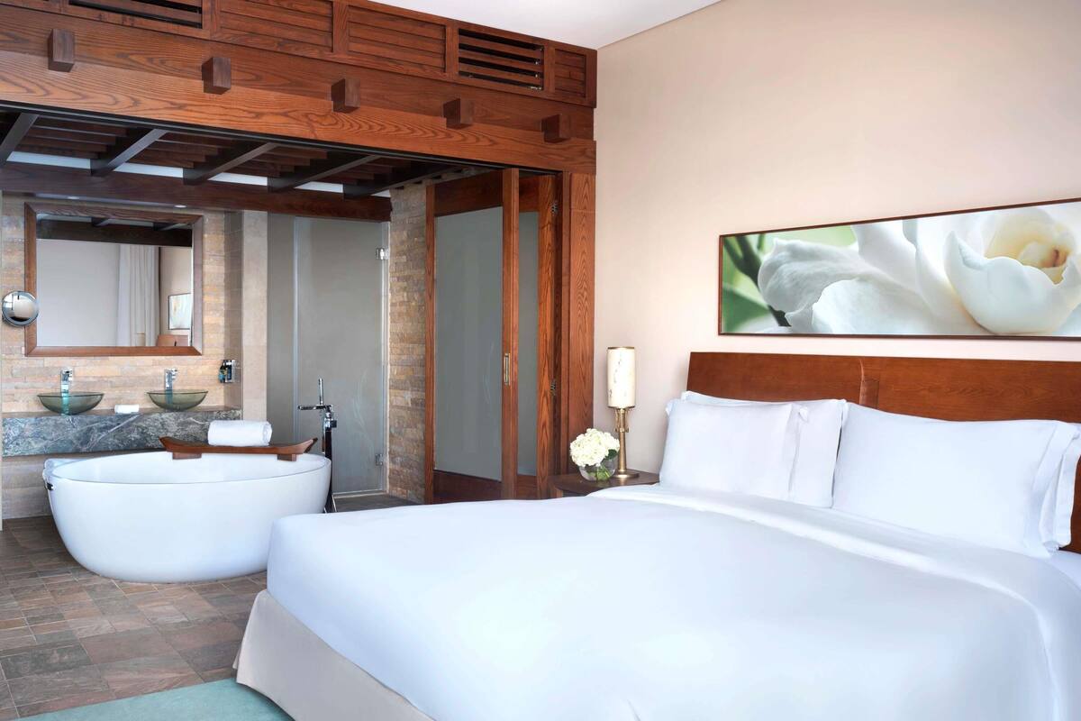 Een moderne hotelkamer met een groot bed, een badkuip en een aparte douche.