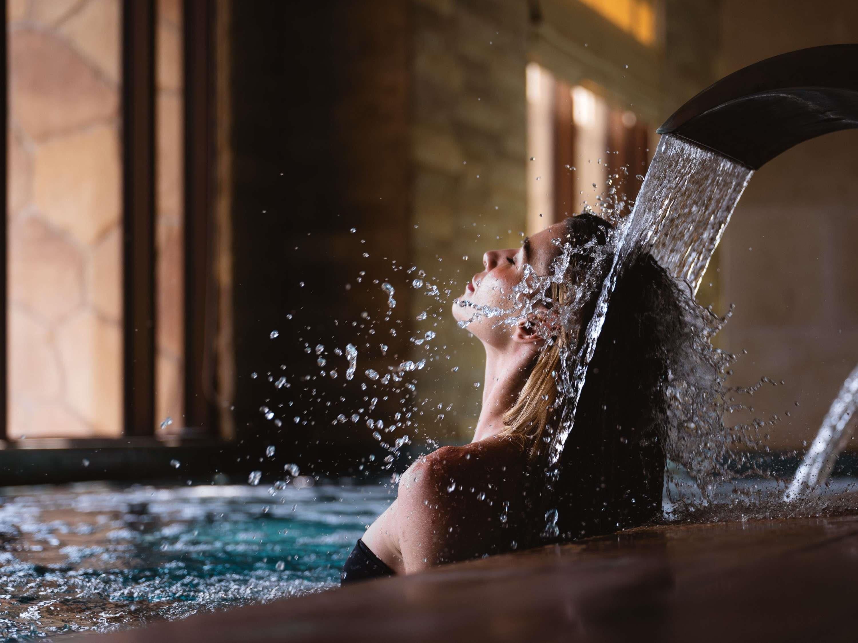 A person in a hot tub with water splashing around them.