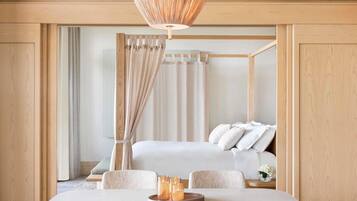 A modern bedroom with a wooden four-poster bed, a dining table with chairs, and a hanging light fixture.