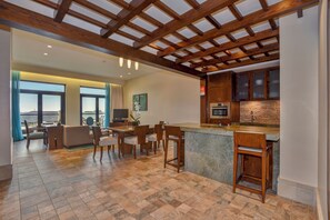 A spacious living area with a wooden ceiling, a kitchen with a stone countertop, and a dining area with chairs and a table. - Sofitel Dubai The Palm Resort & Spa (Dubai)