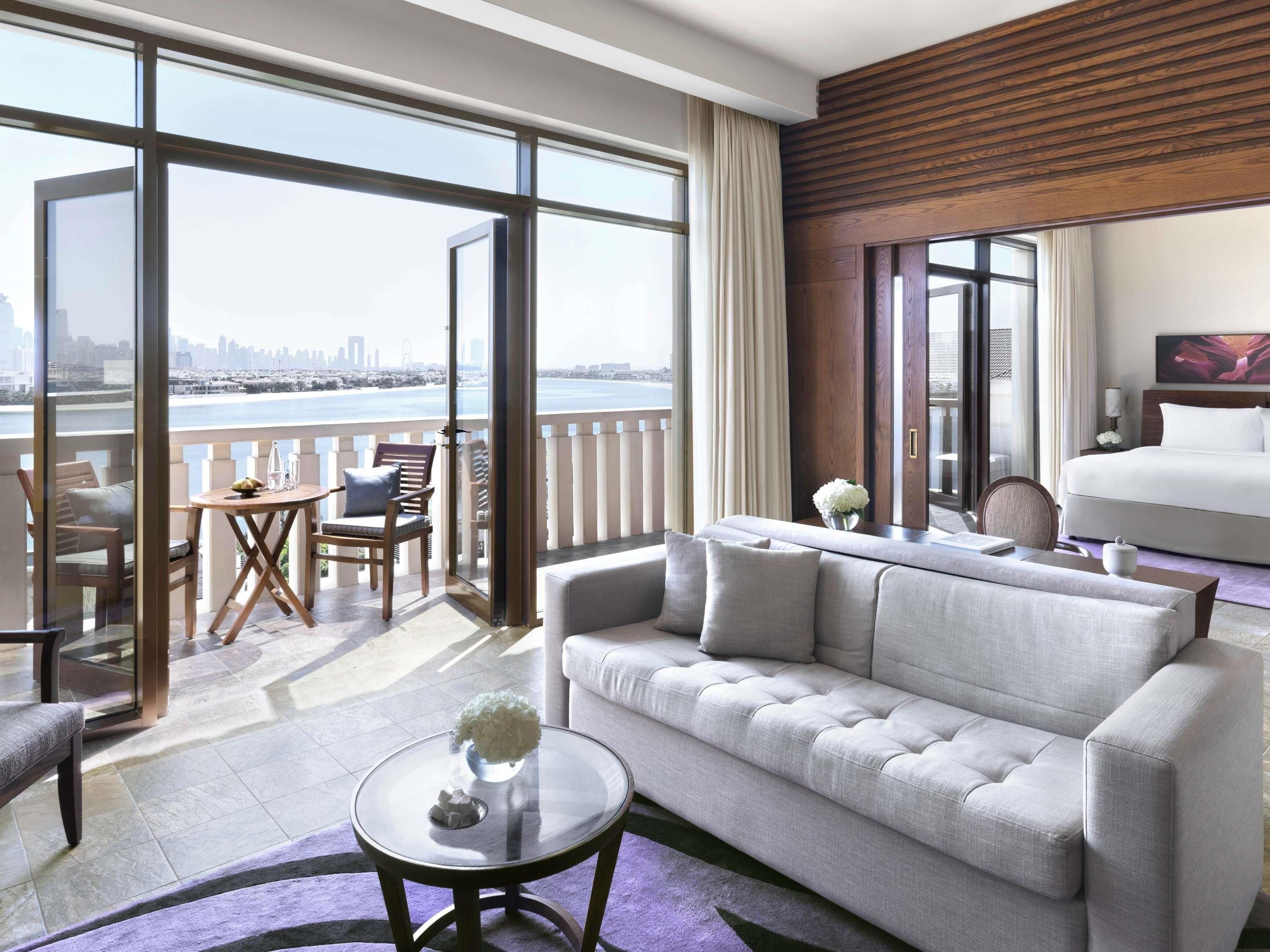 Une chambre d’hôtel moderne dotée d’un balcon, d’un canapé, d’une table à manger et d’un lit.