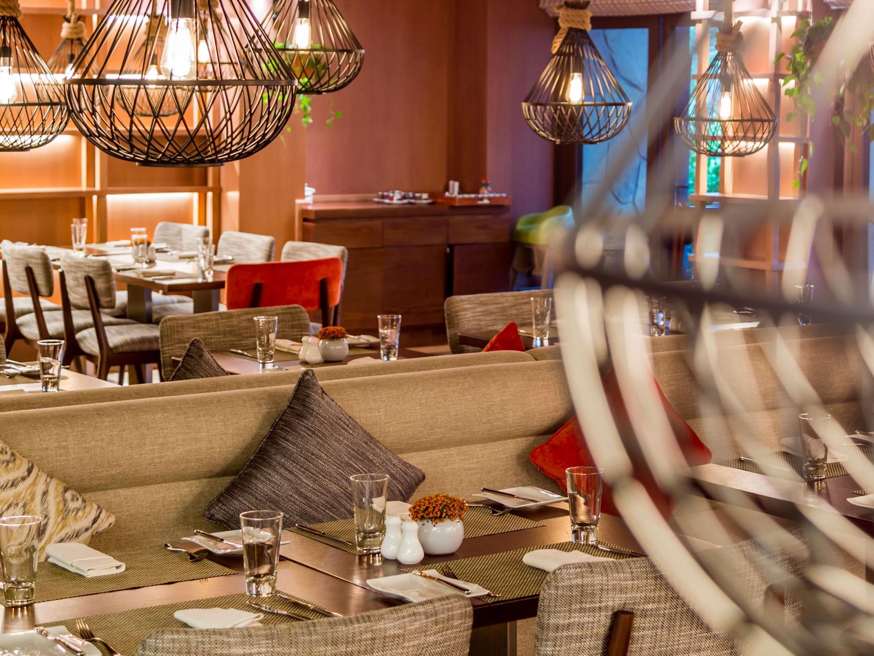 A restaurant with multiple dining tables, chairs, and hanging light fixtures.