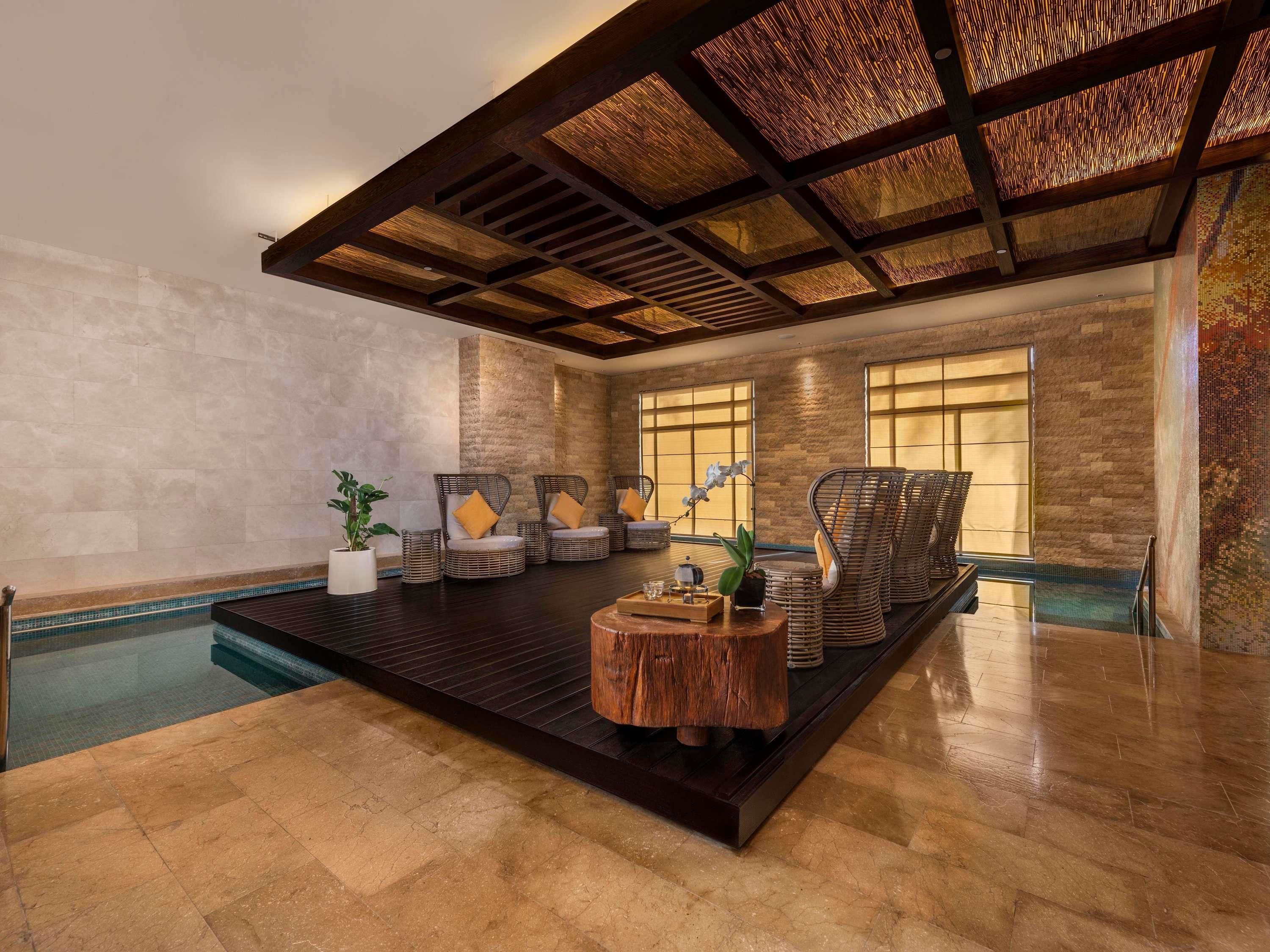 A spacious indoor area with a pool, wicker chairs, and a wooden coffee table.