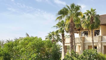 A building with a stone facade, multiple balconies, and lush greenery surrounding it.