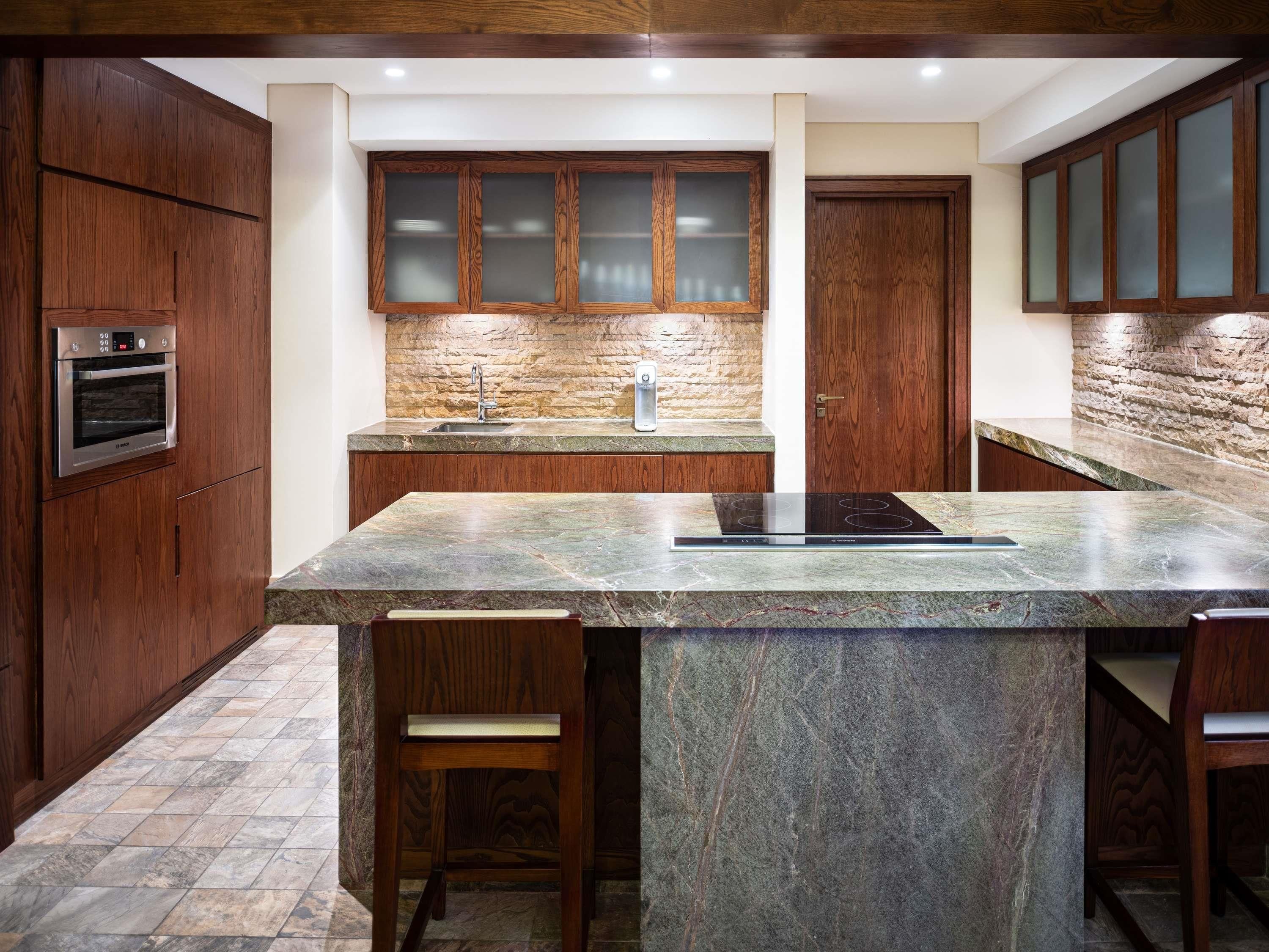 A modern kitchen with wooden cabinets, a stone backsplash, and a central island with seating.
