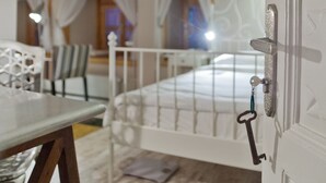 Un dormitorio con una cama, una mesita de noche, una silla y una ventana con cortinas.