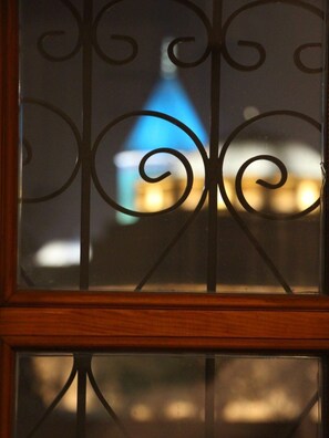 A window with decorative iron bars and a view of a building with a blue roof. - Hich Hotel Konya (Konya)