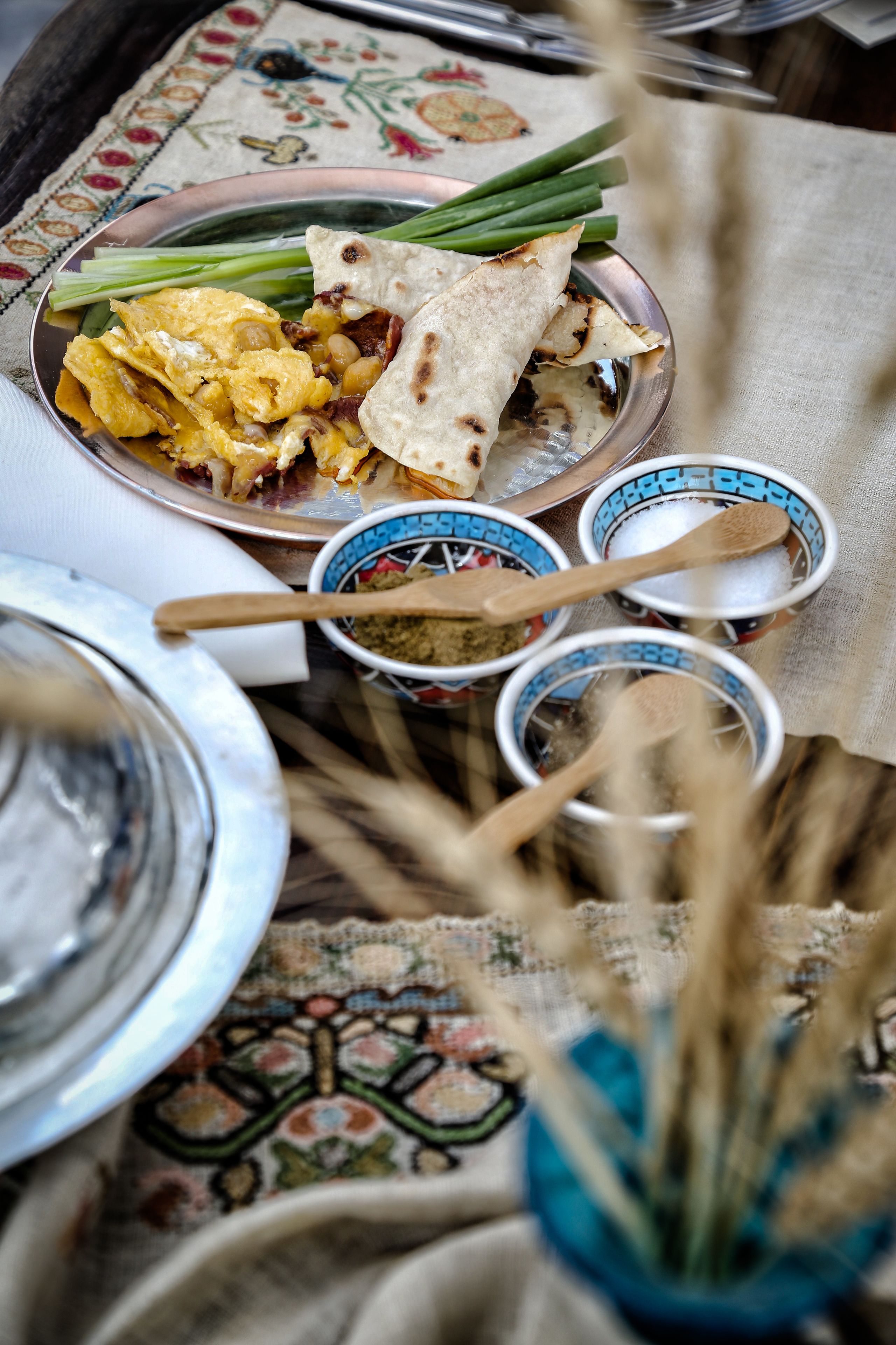 Un repas traditionnel composé de galettes, de légumes et d’épices, le tout disposé sur une nappe à motifs.