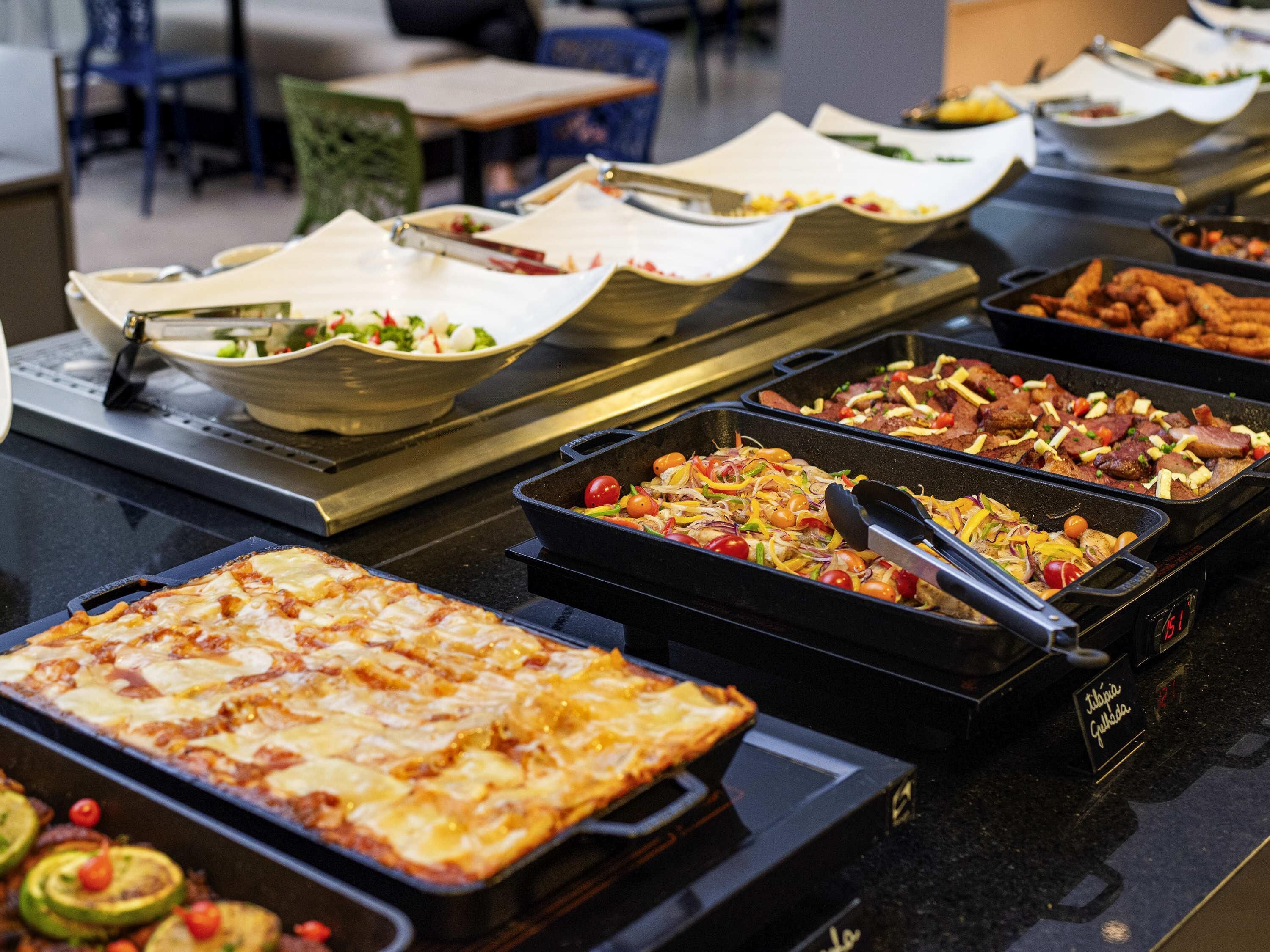 A buffet with various dishes, including a pizza, salads, and meats.