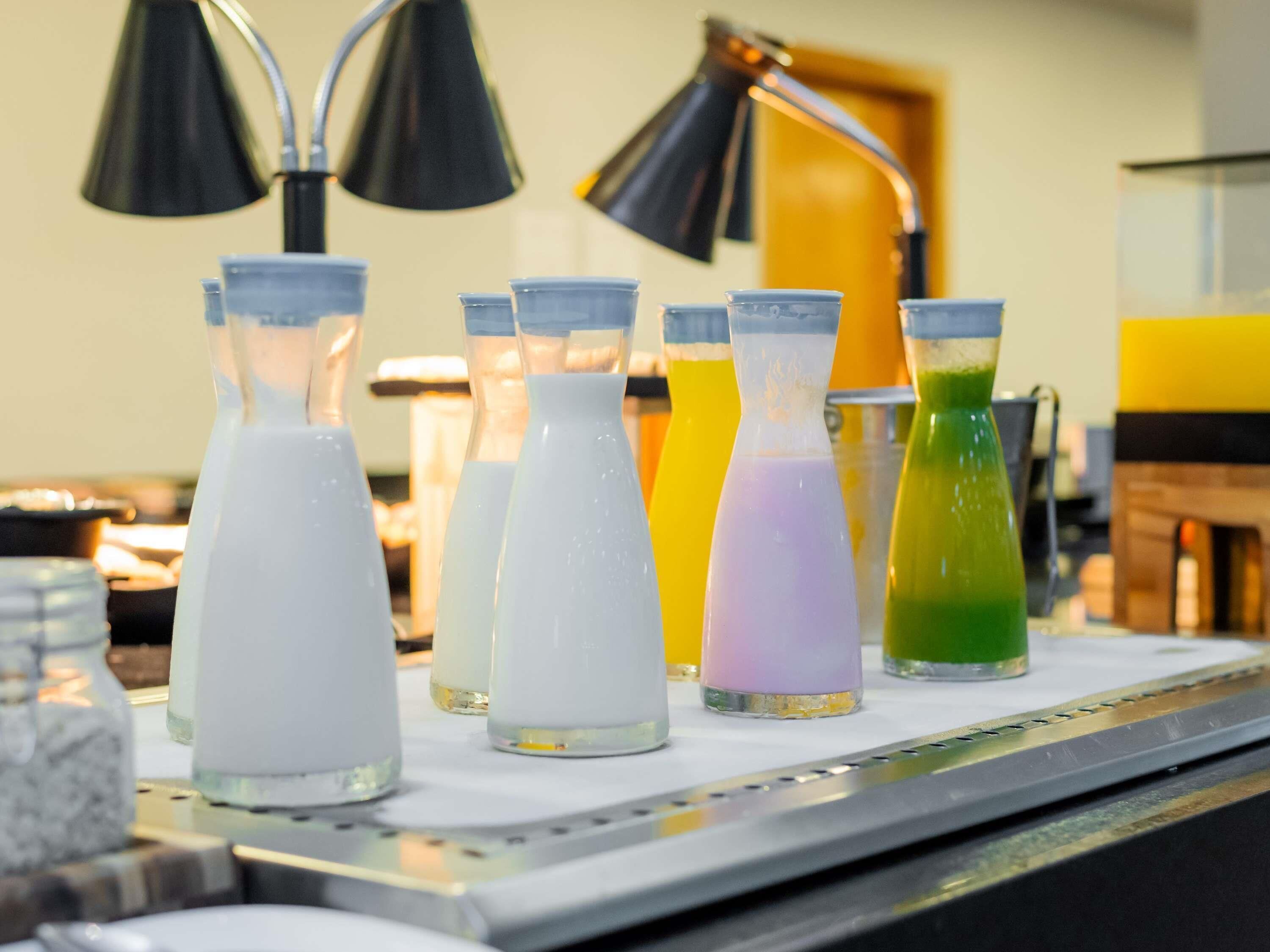 Une rangée de bouteilles en verre contenant différents liquides de couleurs variées, posées sur un comptoir.