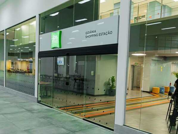 A modern shopping station with glass walls, a green logo, and a sign indicating it's a GOINIA shopping station.