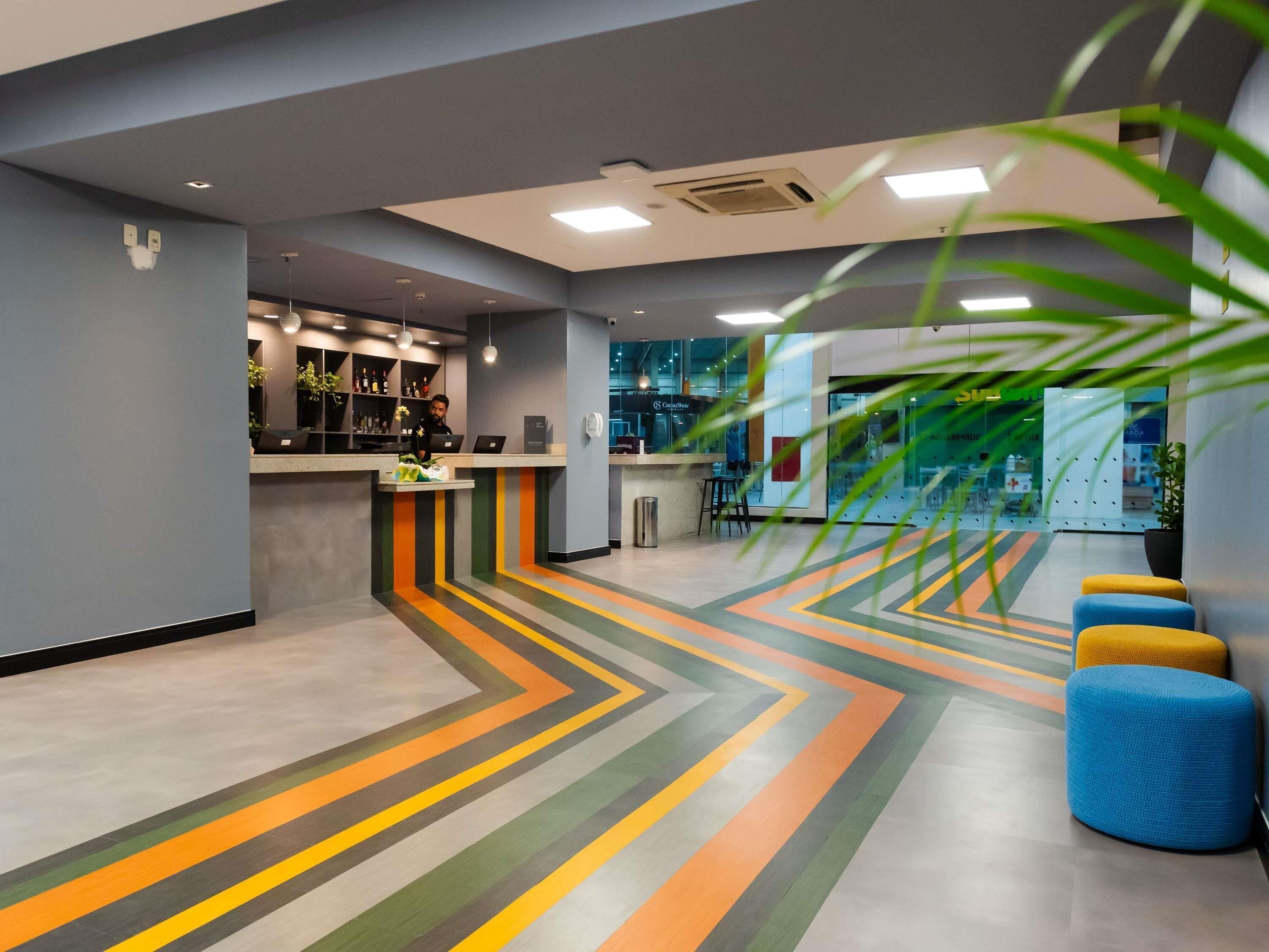 Un vestíbul modern amb una recepció, zona de seients i un paviment amb motius.
