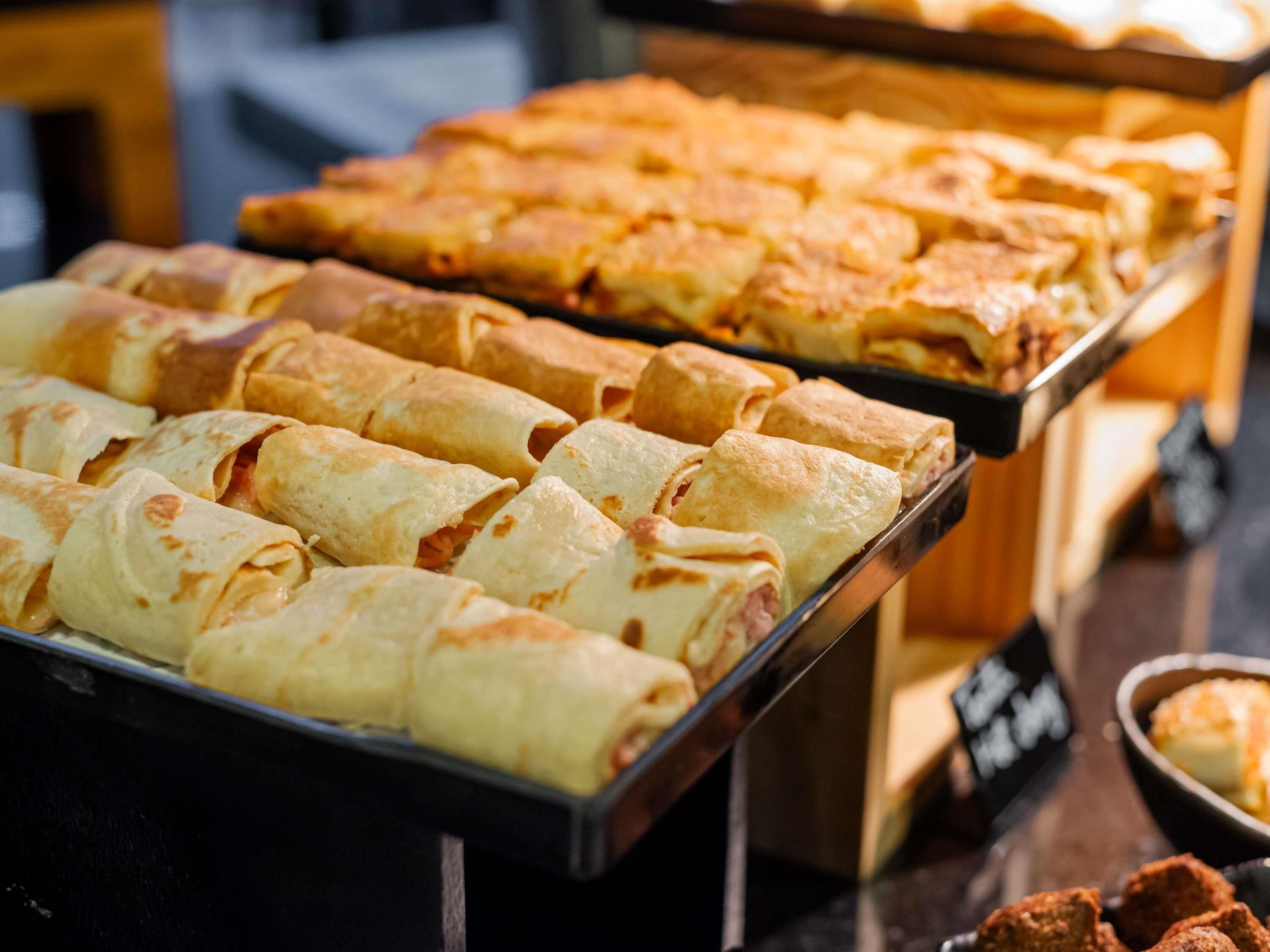 Un buffet proposant une variété de plats, notamment des pâtisseries enroulées et des galettes.