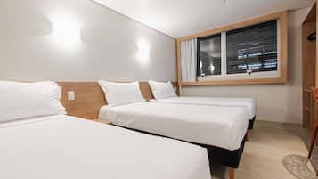 A hotel room with two beds, a window with blinds, a wooden headboard, and a light switch on the wall.