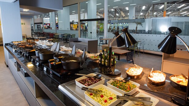Un espace buffet proposant différents stands de nourriture et divers types de tables et de chaises.