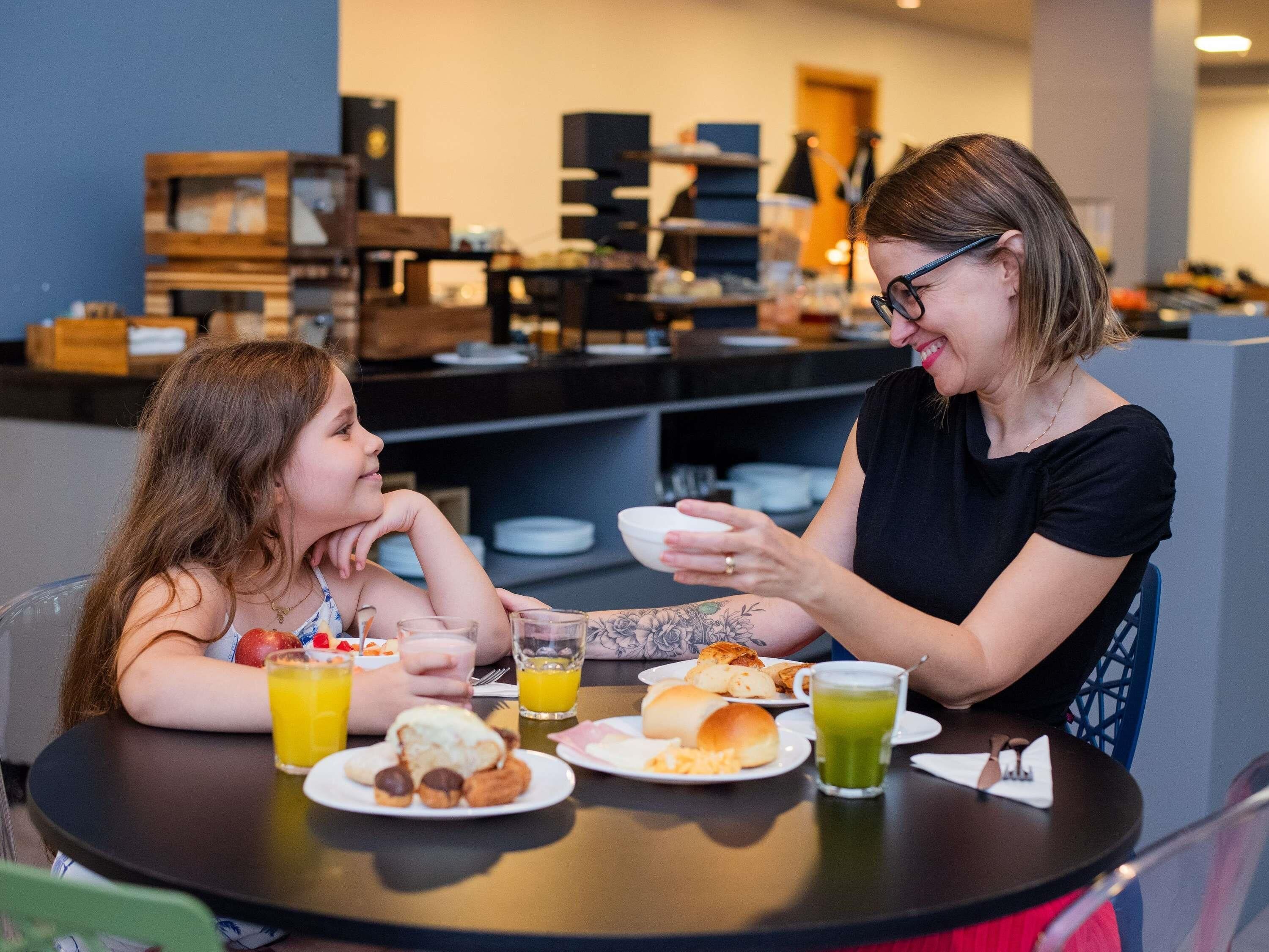 Deux personnes sont assises à une table, devant un petit-déjeuner composé de divers aliments et de boissons.