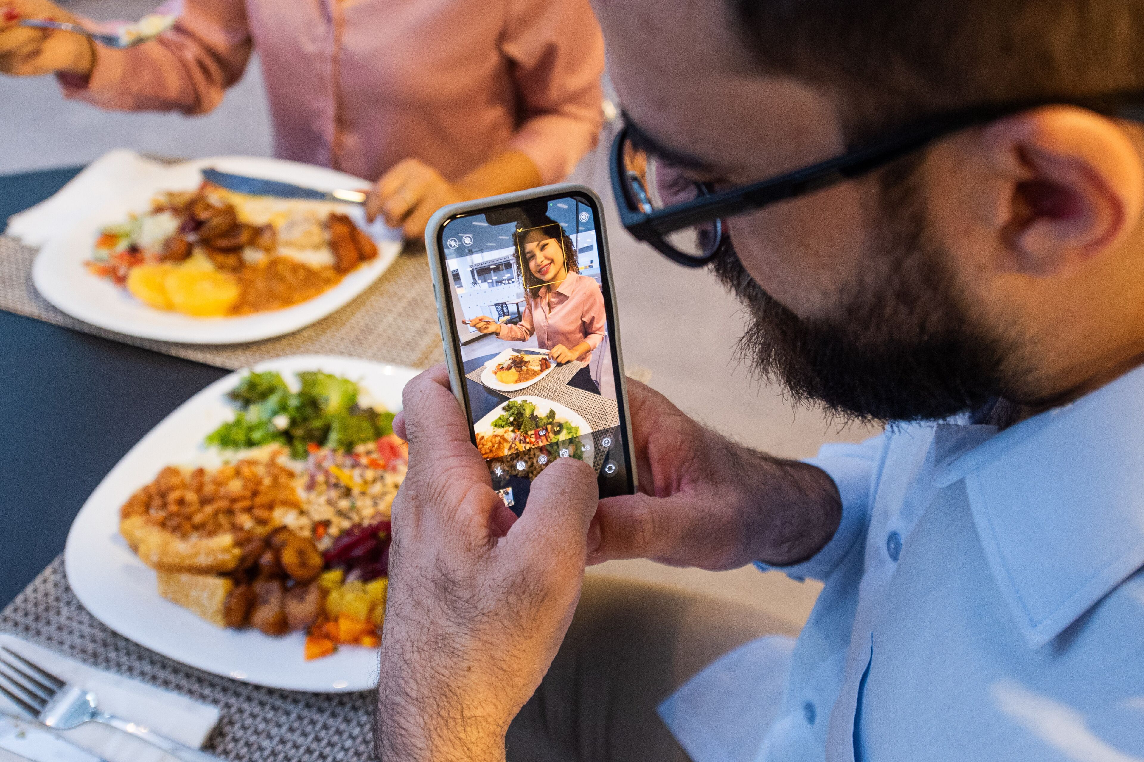 A person holding a smartphone with a photo of a meal on the screen.