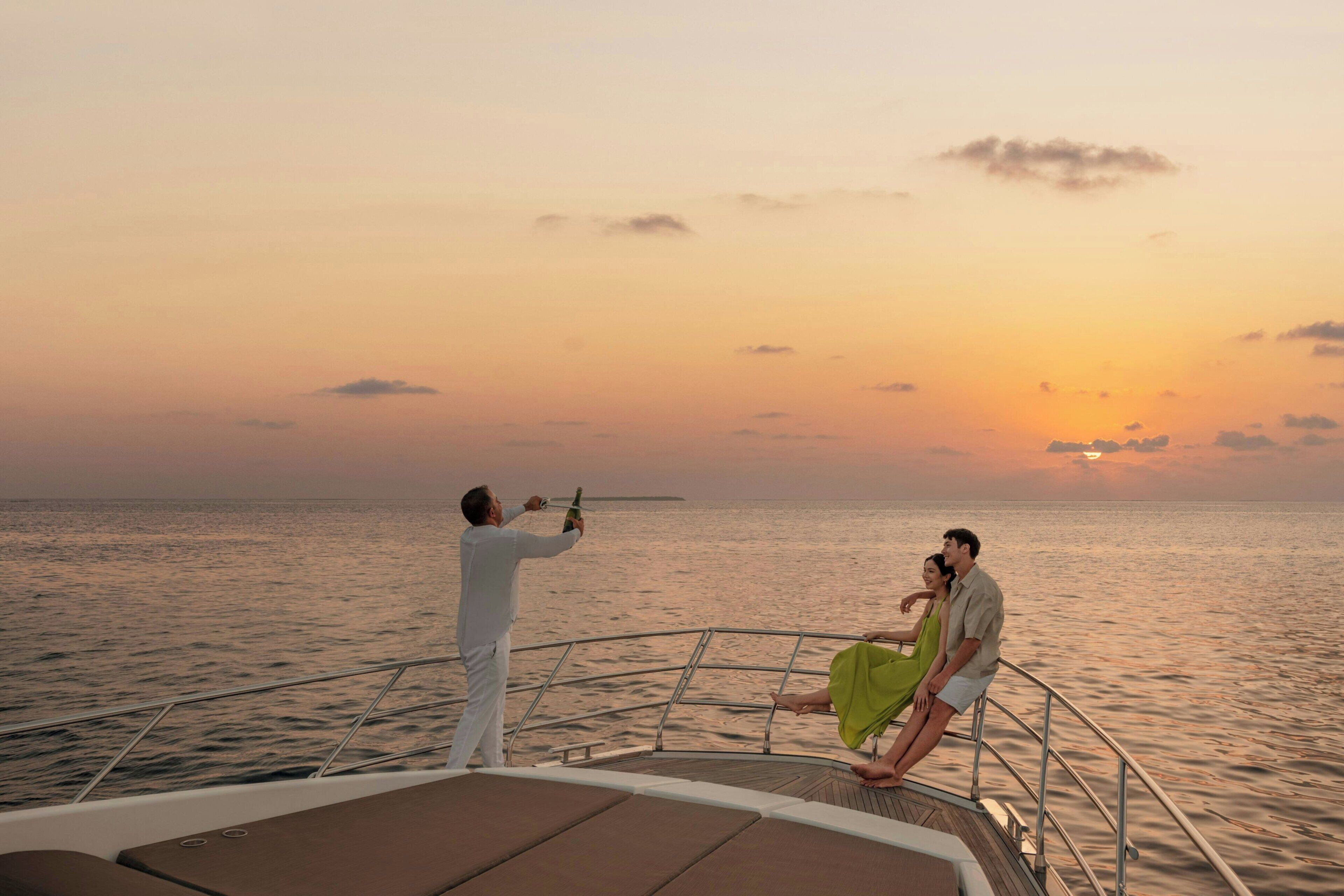 A boat with a metal railing, a person holding a bottle, and another person sitting on the deck.