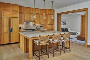 A modern kitchen with wooden cabinets, a marble island, and bar stools.