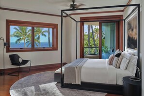 A bedroom with a four-poster bed, a view of the ocean, a chair, and a large window.