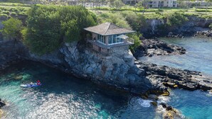 Un hôtel en bord de mer offrant une vue sur l’océan, un promontoire rocheux et un petit bâtiment situé au sommet de la falaise.