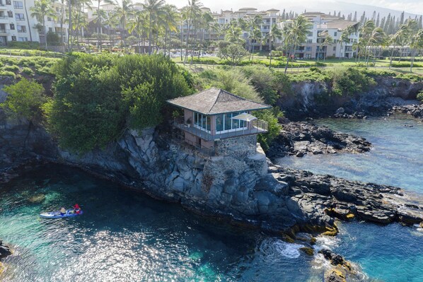 Un hôtel en bord de mer offrant une vue sur l’océan, un promontoire rocheux et un petit bâtiment situé au sommet de la falaise.