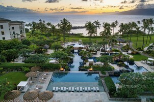 A resort with a swimming pool, lounge areas, and a view of the ocean.