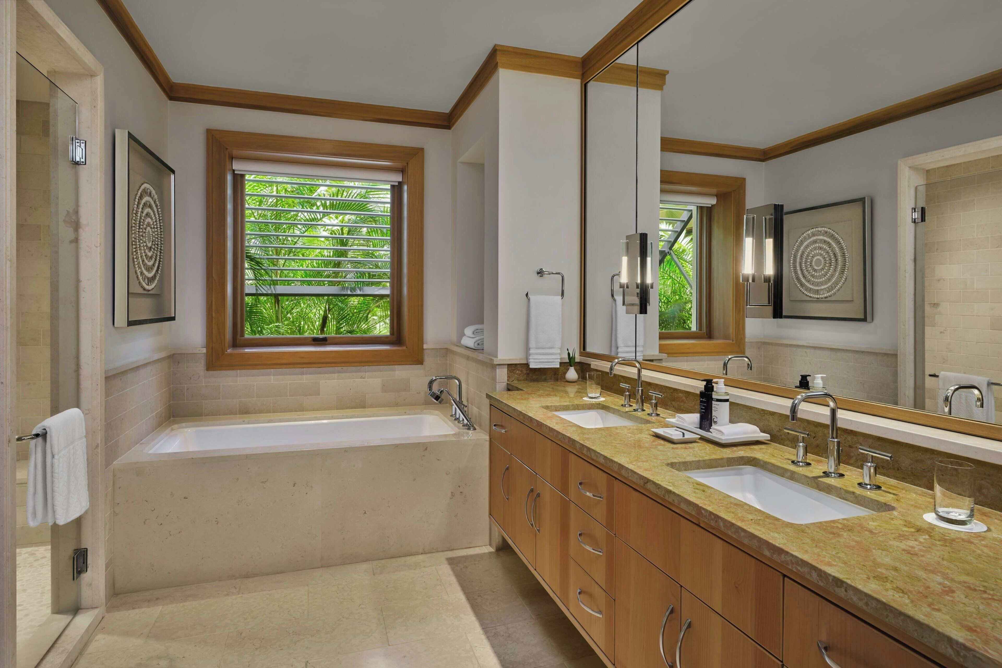 A modern bathroom with a large bathtub, two sinks, and a large mirror.