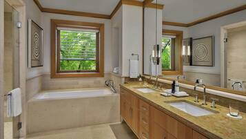 A modern bathroom with a large bathtub, two sinks, and a large mirror.