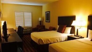 A hotel room with two beds, a desk, a chair, and a window with blinds. - The Sagebrush Hotel (Crystal City)