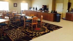 A dining area with tables and chairs, a counter with a coffee machine, and a patterned rug. - The Sagebrush Hotel (Crystal City)