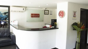 A hotel reception area with a reception desk, a clock, a framed certificate, and a potted plant. - Hotel Innova Chipichape (Cali)