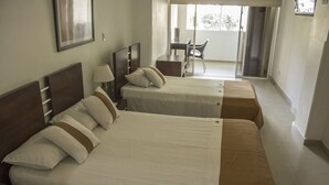 A hotel room with two beds, a desk, and a chair. - Hotel Innova Chipichape (Cali)