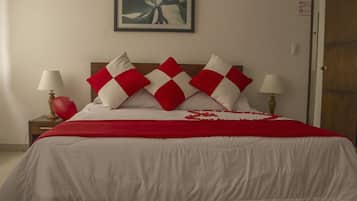 Una cama con un arreglo de almohadas a cuadros rojos y blancos, una manta roja y una decoración con forma de corazón sobre la cama.